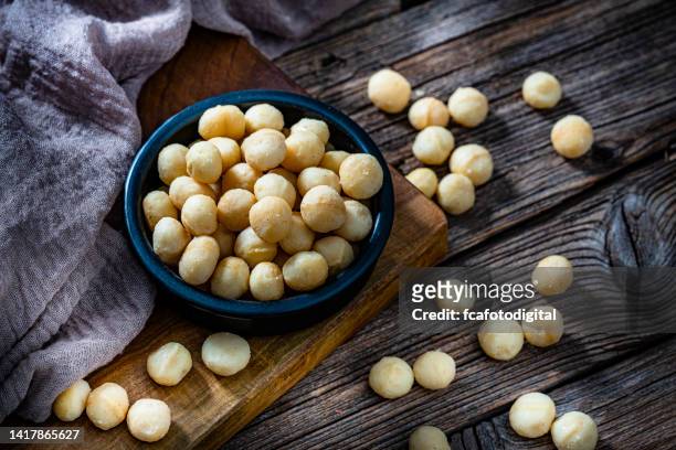 macadamia nuts bowl on dark rustic table - macadamia nut 個照片及圖片檔