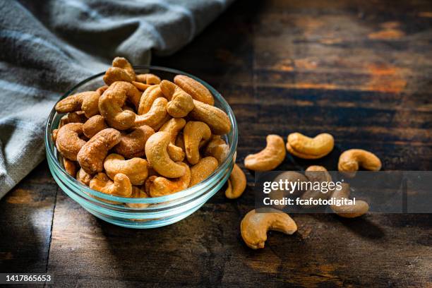 cashew on dark rustic table - cashew stockfoto's en -beelden