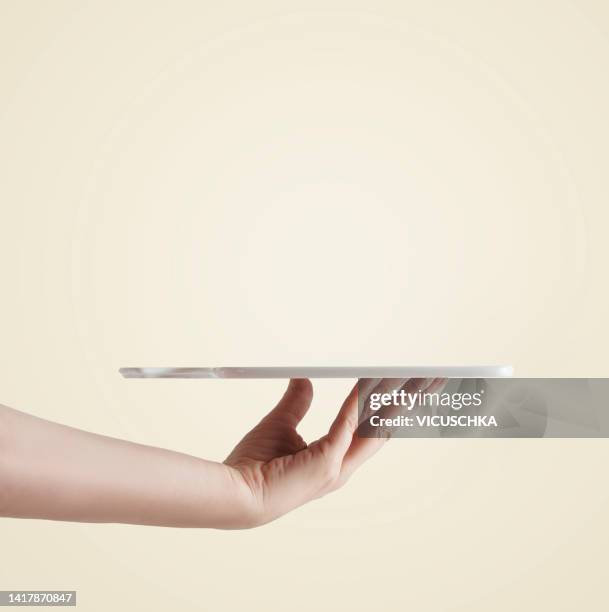 women hand holding empty tray at light background. - empty plate hands stock pictures, royalty-free photos & images