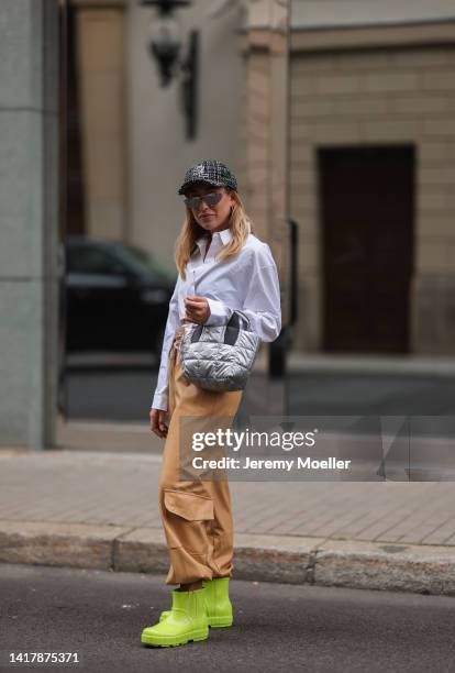 Sonia Lyson is seen wearing Storets white cropped blouse, Saint Laurent black and white logo cap, Ugg neon green puddle boots, The Frankie Shop light...