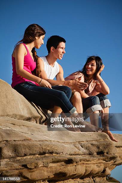 twenty-year-olds sitting on rocks at the beach - 18 year stock-fotos und bilder