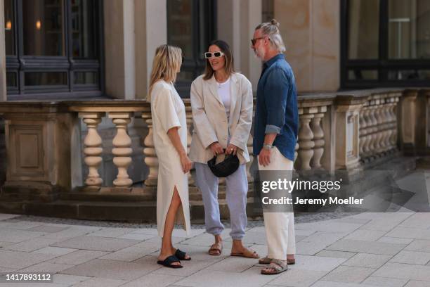 Anne Philine seen wearing black Celine sunglasses, a creme white SohoStudios maxi dress Elise and black leather sandals; Elise Seitz seen wearing...