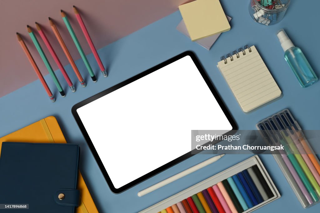 Top view digital tablet with empty screen and school stationery on blue background. Back to school concept.