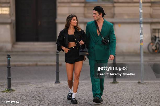 Jessica de Oliveria is seen wearing white socks, black Aldo loafer, Jacquemus black Chiquito leather bag and black and gold matching cropped top,...