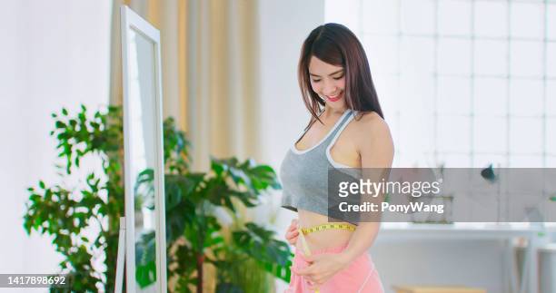 girl measuring waist satisfied - fat loss stock pictures, royalty-free photos & images