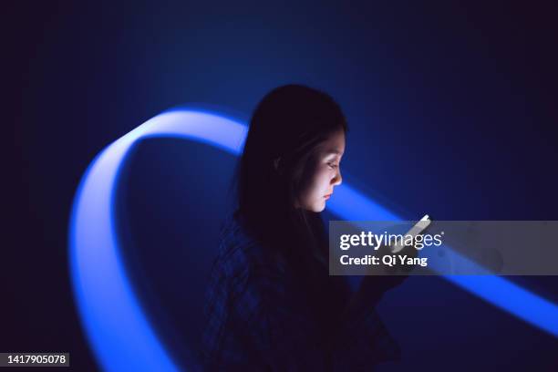 young asian woman using smartphone on the holographic background. metaverse and ai - light trail imagens e fotografias de stock