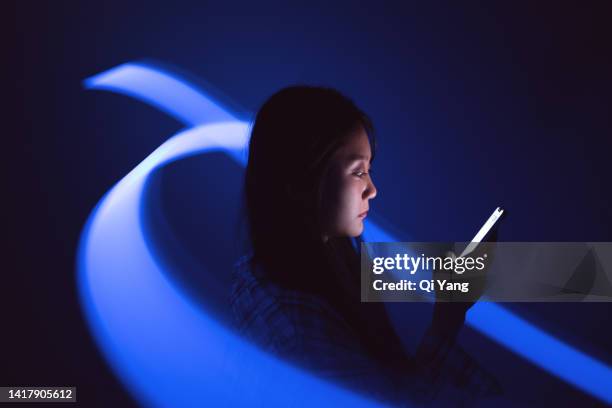 young asian woman using smartphone on the holographic background. metaverse and ai - smartphone hologram stock-fotos und bilder