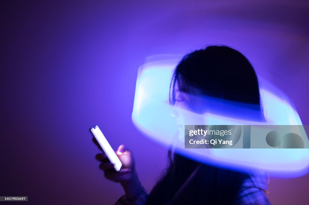 Young Asian woman using smartphone on the holographic background. Metaverse and AI