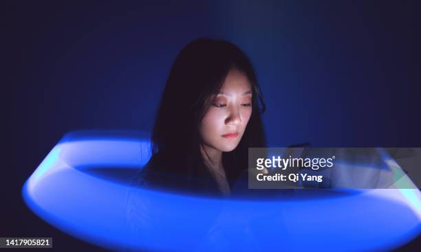 young asian woman using smartphone on the holographic background. metaverse and ai - surrounding imagens e fotografias de stock