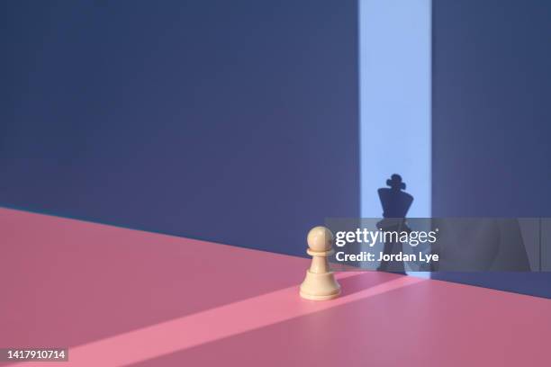 pawn chess piece with king shadow - chess game stock-fotos und bilder