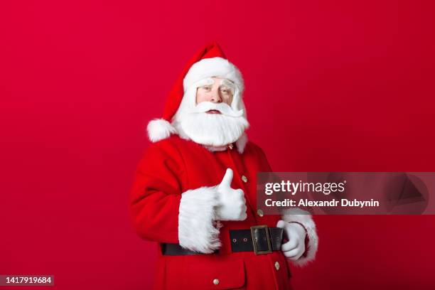 santa claus showing thumbs up gesture on red background - santa clause stockfoto's en -beelden