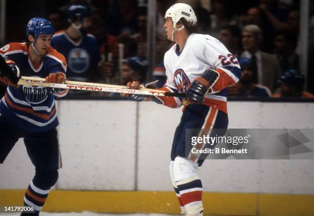 Mike Bossy of the New York Islanders grabs the stick of Kevin Lowe of the Edmonton Oilers during the 1983 Stanley Cup Finals in May, 1983 at the...