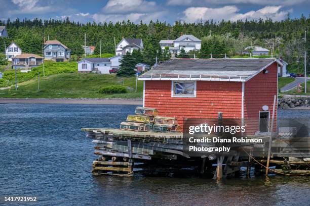 fishing hut with stacked lobster traps in louisbourg harbor, louisbourg, cape breton island, nova scotia, canada - fishing hut stock pictures, royalty-free photos & images