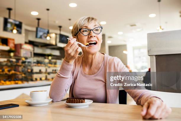 lächelnde ältere frauen mit einem stück dessert - man eating pie stock-fotos und bilder