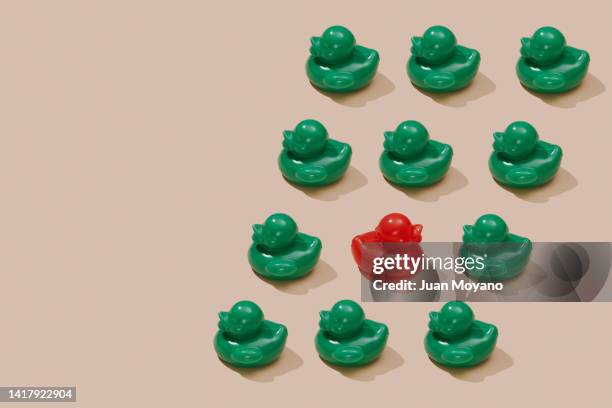red rubber duck upstream between some green rubber ducks - reversing stock pictures, royalty-free photos & images