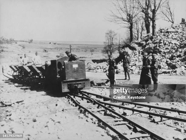 Officers of the Nazi SS and the Reich Labour Service oversee the industrial demolition and levelling of the village of Lidice circa mid July 1942 in...