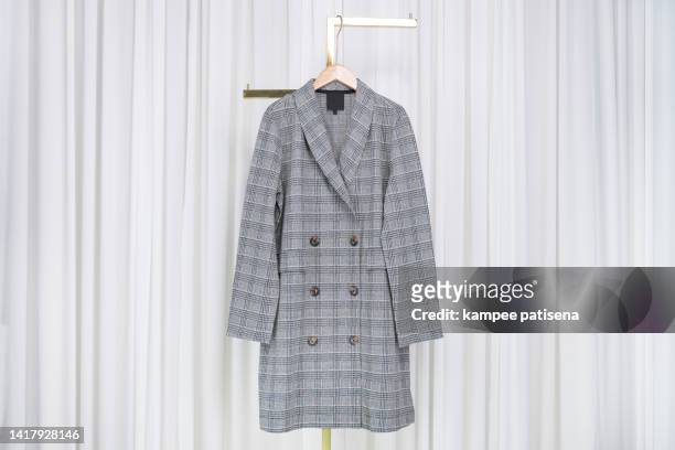 plaid grey overcoat hanging in home - vintage raincoat stock-fotos und bilder