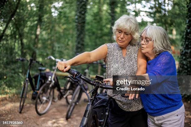 portrait of two senior women biking outdoors on an outdoor adventure - cycling netherlands stock pictures, royalty-free photos & images