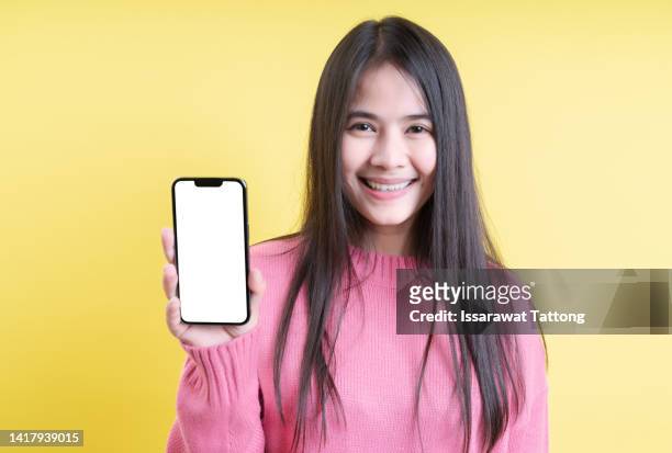 young beautiful woman holding blank screen smart phone on pink background - tonen stockfoto's en -beelden