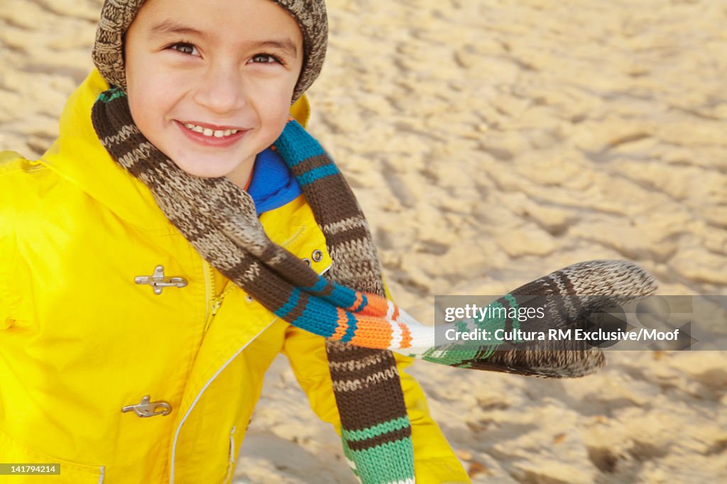 Smiling boy running on beach in winter