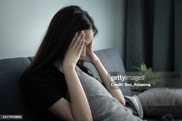 depressed woman sitting alone on sofa. depression is a form of highly negative thinking towards oneself, others and life. - anxiety foto e immagini stock