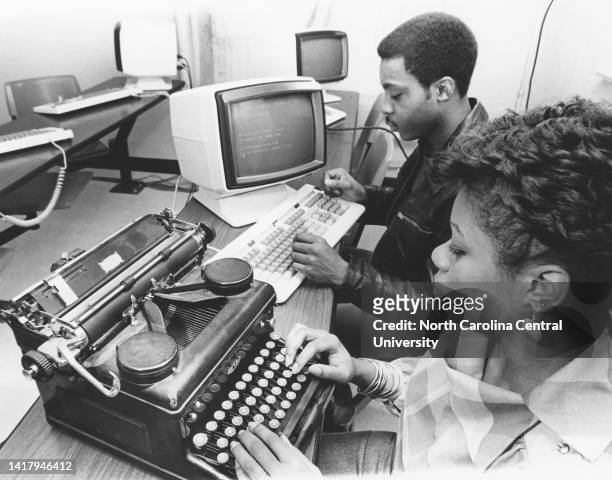 African American woman using a Royal typewriter while a African American man is typing on a computer keyboard on the North Carolina Central...