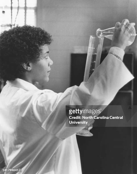 North Carolina Central University Student, African American woman pouring chemical in laboratory equipment.