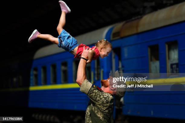 Ukrainian soldier Oleksandr lifts his two year old daughter Nikole after they disembarked a train from Zaporizhia at Lviv railway station on August...