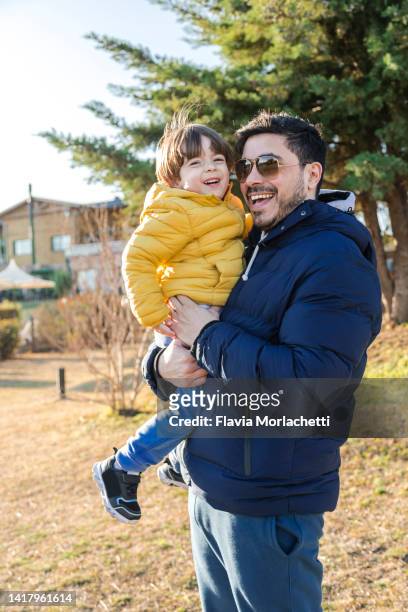 father holding son on arms and laughing - córdoba argentina stock pictures, royalty-free photos & images