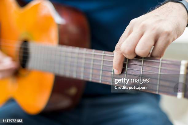 young man playing acoustic guitar at home - fretboard stock pictures, royalty-free photos & images