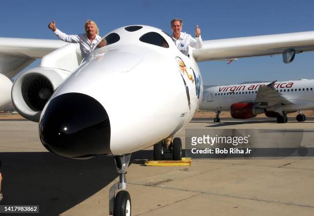 Virgin Group Founder Sir Richard Branson and aviation pioneer Burt Rutan wave to guests during the official roll-out of Virgin Galactic's...