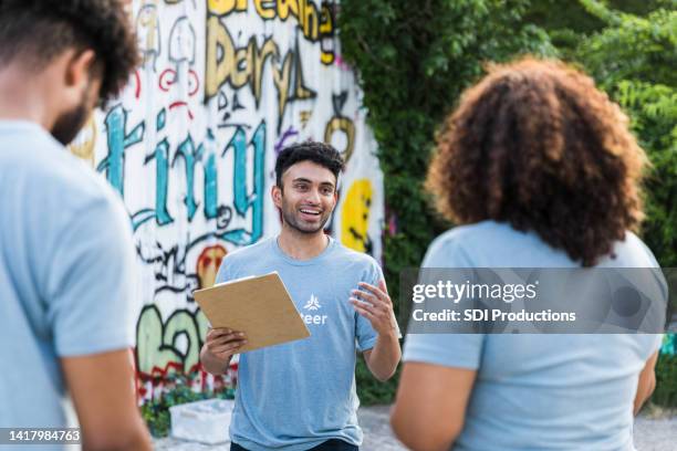 männlicher freiwilligenkoordinator für junge erwachsene erklärt graffiti-aufräumprojekt - arab community life stock-fotos und bilder