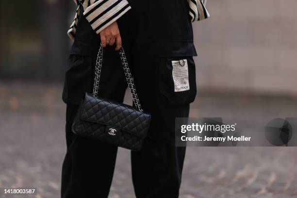 Julia Zwingenberg wearing striped black and beige Arket sweater, Chanel medium black leather flap bag, Preach wide leg pants on August 22, 2022 in...