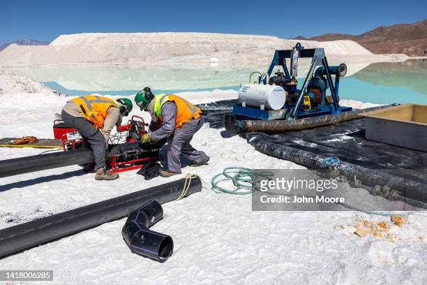 Lithium mine workers inspect machinery at an evaporation pond in the Atacama Desert on August 24, 2022 in Salar de Atacama, Chile. Albemarle...