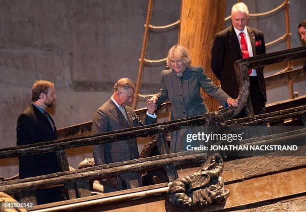 Britain's Prince Charles helps his wife, Camilla, as they walk on the Swedish warship Vasa at the Vasa Museum in Stockholm on March 24, 2012. Prince...