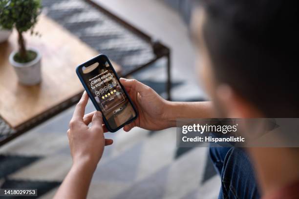 man at home rating his experience using a mobile app - customer experience stock pictures, royalty-free photos & images