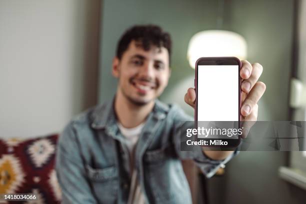 young man holding mobile device with white screen - hand showing stockfoto's en -beelden