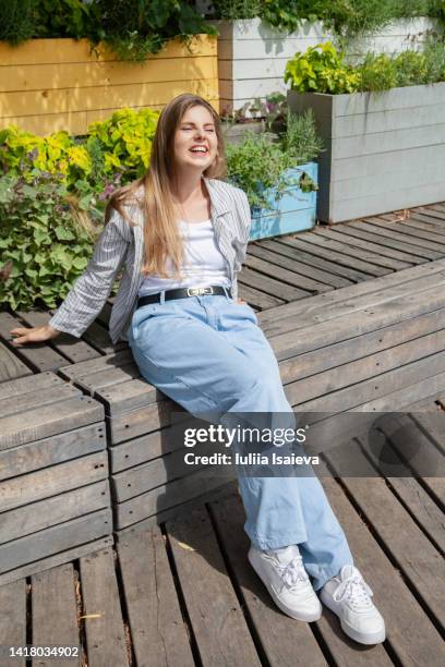 young female resting on wooden border in park - daylight saving time 2021 stock pictures, royalty-free photos & images