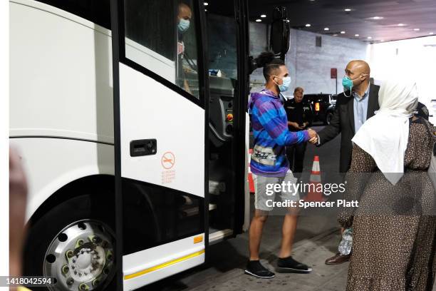 Migrants who crossed the border from Mexico into Texas exit a bus as it arrives into the Port Authority bus station in Manhattan on August 25, 2022...