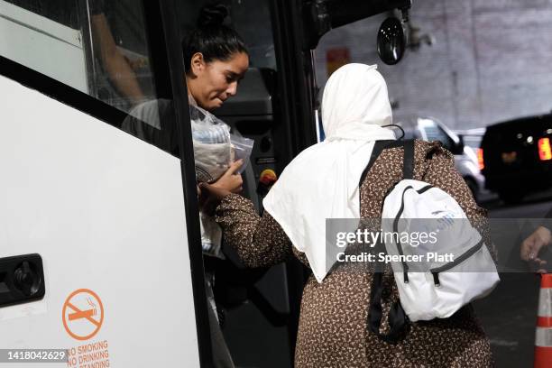 Migrants who crossed the border from Mexico into Texas exit a bus as it arrives into the Port Authority bus station in Manhattan on August 25, 2022...