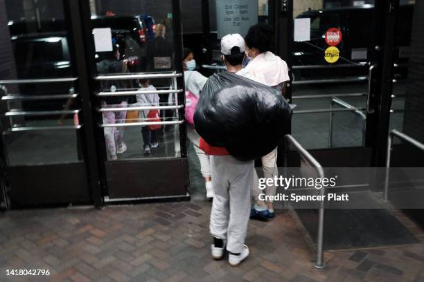 Migrants who crossed the border from Mexico into Texas walk through the Port Authority bus station in Manhattan after arriving by bus on August 25,...