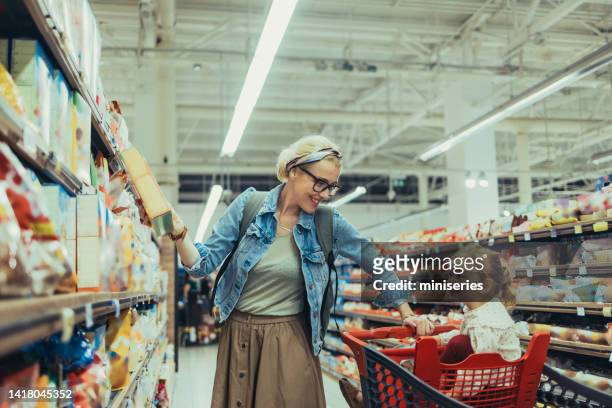 mom and daughter shopping together in the supermarket - cereal box stockfoto's en -beelden