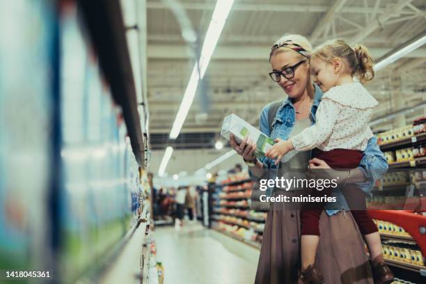 maman et sa fille font leurs courses ensemble au supermarché - mom buying milk photos et images de collection