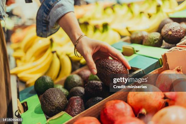 une femme anonyme choisit des avocats au supermarché - avocat légume photos et images de collection