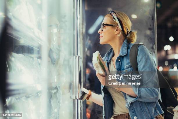 retrato de una mujer hermosa que elige productos de una nevera en el supermercado - congelador fotografías e imágenes de stock