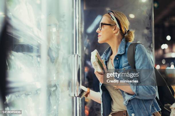 portrait of a beautiful woman choosing products from a fridge in the supermarket - convenience stock pictures, royalty-free photos & images