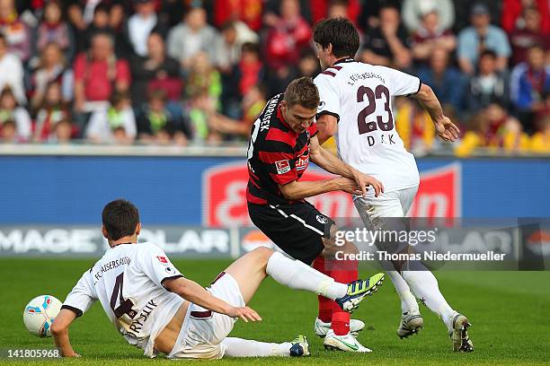 Erik Jendrisek of Freiburg fights for the ball with Ariel Borysiuk and Florian Dick of Kaiseslautern during the Bundesliga match between SC Freiburg...