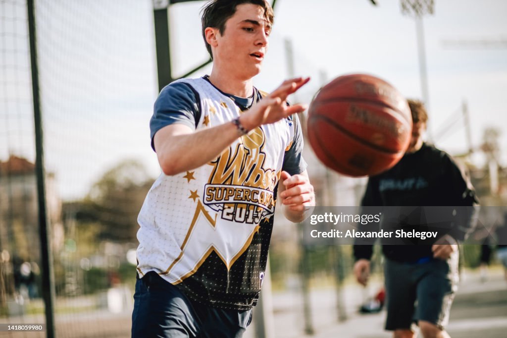 People playing streetball at the street. Sports photography with basketball. City life concept. Person using ball for game.