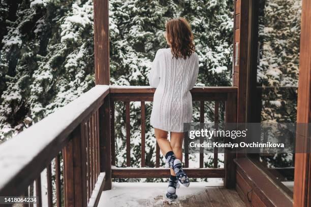 cute young caucasian teenage woman in beige fur coat, hat with pompon, scarf and white mittens holding steaming white cup of hot tea or coffee, outdoor in sunny winter day. bask in the cold - woman hands in mittens stock-fotos und bilder