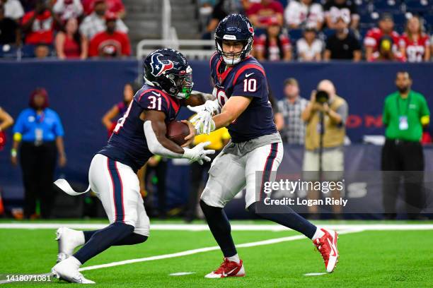 Davis Mills hands the ball off to Dameon Pierce of the Houston Texans in the first quarter during a preseason game against the San Francisco 49ers at...